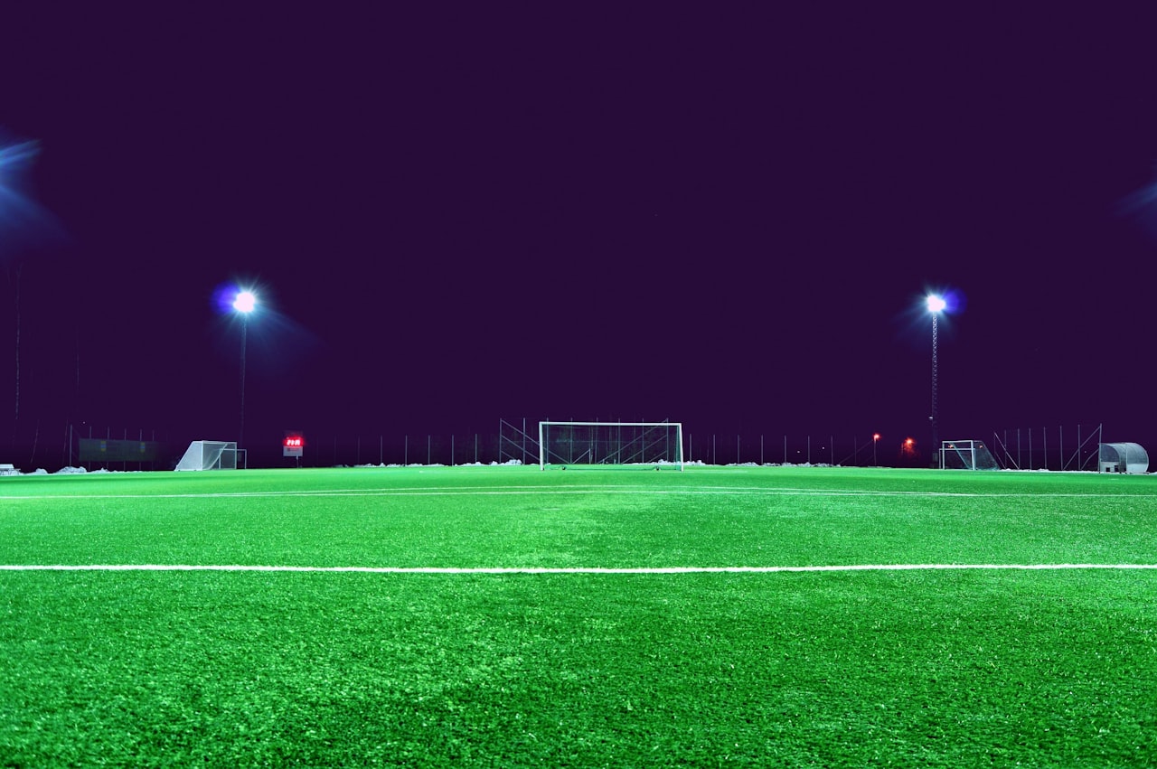An empty floodlit pitch at night, the quiet erosion of framework drift.